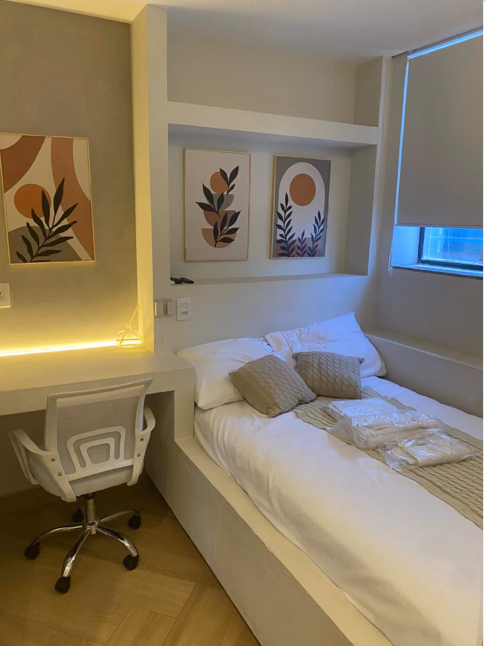Quarto com duas beliches de metal preto, cada uma com cama de cima e de baixo, roupas de cama brancas, toalhas dobradas e paredes branca e verde.